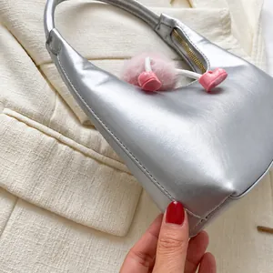 Detailed macro of silver metallic shoulder bag with pink faux fur heart pendant