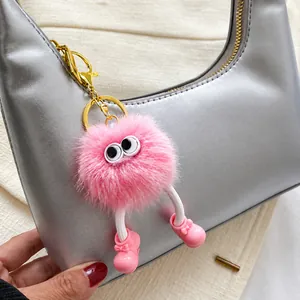 Close-up of pink furry monster bag charm with big eyes and gold metal clasp