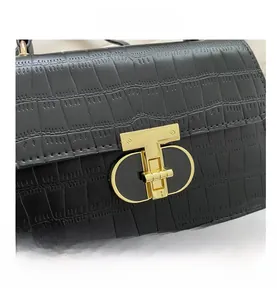 Detailed macro shot of a black crocodile-textured handbag with a gold T-shaped twist lock