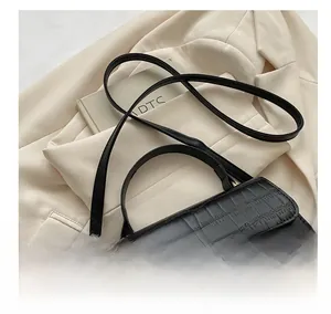 Detailed view of black crocodile pattern leather bag with elegant gold metal buckle