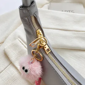 Close-up of golden smooth zipper and leather texture with a cute pink plush charm