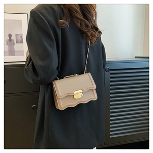Detail of khaki crossbody bag with wavy edge flap and gold square metal lock clasp