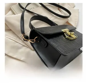Detail of black crocodile texture handbag with premium gold metal clasp and buckle