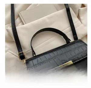 Detail of glossy black crocodile texture bag featuring a unique gold geometric T-lock
