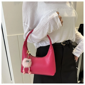 Macro detail of fuchsia half-moon bag featuring a cute pink plush monster charm