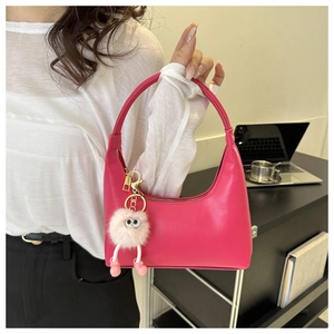 Close-up of hot pink crescent hobo bag with a cute pink plush monster bag charm