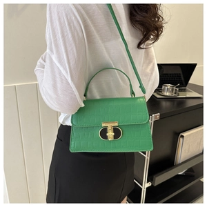 Close-up of vibrant green faux crocodile leather bag with a gold T-shaped clasp detail
