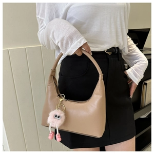 Close-up of minimalist beige hobo bag with a decorative pink plush monster charm