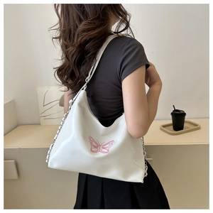 Detail view of a white soft leather hobo bag with pink butterfly embroidery and chain strap