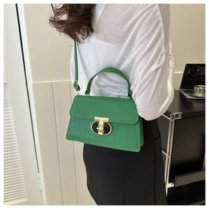 Green faux crocodile texture handbag featuring a unique gold metal clasp on a crossbody bag