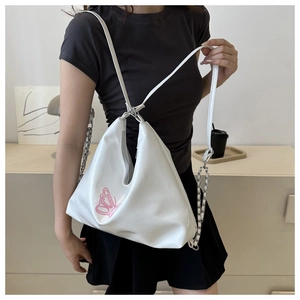 Detailed view of pink butterfly embroidery on soft white leather crescent shoulder bag