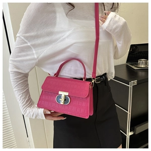 Close-up of fuchsia crocodile pattern leather bag with metallic ring buckle and handle
