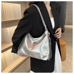 Silver shoulder bag with pink butterfly embroidery and metallic chain on a model