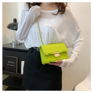 Detail showing wavy flap and gold metal clasp of neon green crossbody chain bag