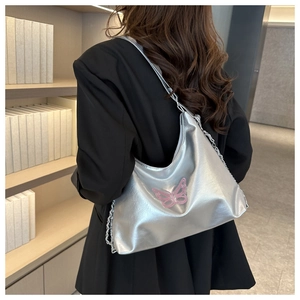 Detail of silver metallic bag featuring pink butterfly embroidery and chain strap