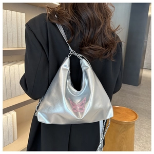 Detail of silver metallic hobo bag with pink butterfly and chain strap on a model