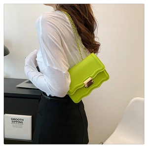 Close-up of neon green crossbody bag with wavy flap and golden chain strap
