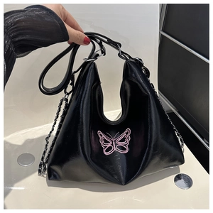 Detailed shot of black high-gloss leather bag with pink butterfly embroidery and silver chain