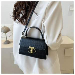 Detail of elegant black crocodile pattern handbag with golden T-shaped metal lock closure