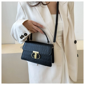 Close-up of black crocodile pattern crossbody bag with gold buckle on white blazer