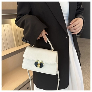Detail of white crocodile pattern handbag with gold twist lock and crossbody strap