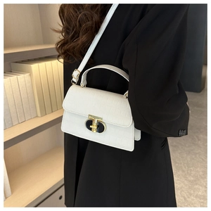 Detail showing white crocodile texture square bag with gold lock on a black suit blazer