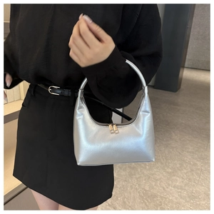 Detail of silver metallic handbag with sleek crescent shape and golden zippers
