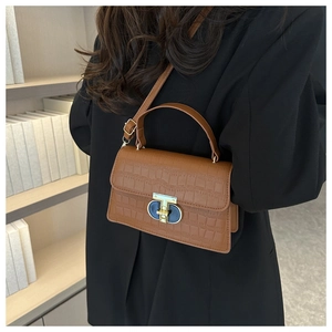 Detailed close-up of brown crocodile texture and gold metal clasp on a stylish handbag