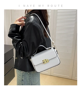 Close-up of structured white handbag with a gold square twist lock and fine shoulder strap