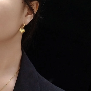 Boucles d'oreilles cœur en or poli et collier assorti sur un modèle féminin