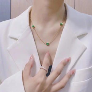 Elegante gouden titanium ketting met groene vierkante hangers bij een vrouwelijk model