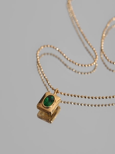 Collier vintage en or avec pendentif zircon vert ovale et chaîne à billes sur miroir