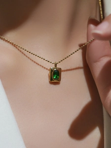 Collier élégant à billes dorées avec pendentif rectangle en zircon vert émeraude sur mannequin