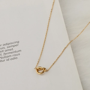 Elegant 18K gold-plated love knot pendant necklace on a minimalist jewelry display card