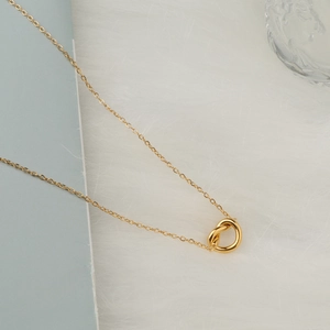 18K gold plated titanium steel knotted pendant necklace on elegant white plush background