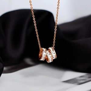 Elegant rose gold triple ring necklace with sparkling zircon pavé on black silk background