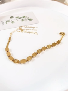 Gold titanium snake bone bracelet featuring LOVE engraved rectangle charms in a ceramic plate