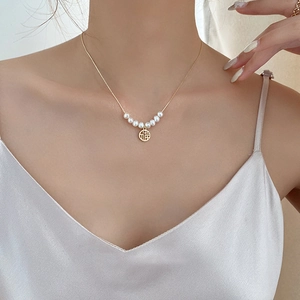 Elegant gold necklace with pearls and Fu character pendant worn by a model