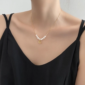 Elegant gold titanium necklace with white pearls and a hollow Fu pendant on model