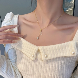 Élégant collier doré en acier titane avec double pendentif gourde et zircons sur pull