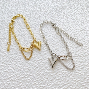 Détail de bracelets cœur en acier doré et argenté avec maille gourmette texturée