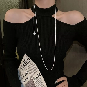 Long silver snake chain necklace with white pearl pendant on model wearing black knitwear