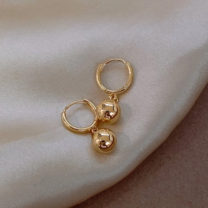 Minimalist gold ball hoop earrings on a silk background with high-polish spherical charms