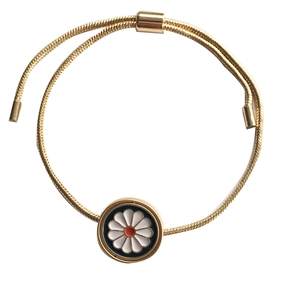 Adjustable golden snake chain bracelet with white daisy pendant on black enamel background