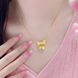 Collier nœud muguet en or 18 carats porté par un mannequin sur un haut rose