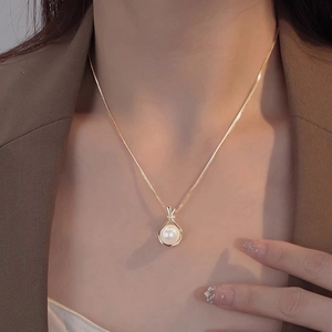 Elegante goldene Titan-Halskette mit Perlenanhänger, präsentiert an einem weiblichen Model