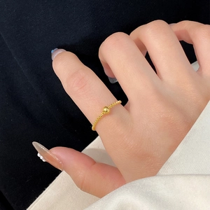 Minimalist gold chain ring with polished bead shown on hand with contrast background