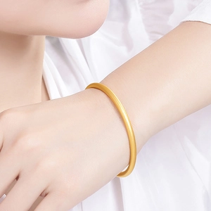 Classic 18K gold plated bangle with a matte frosted finish on a woman's wrist