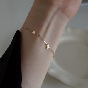 Minimalist gold-plated stainless steel chain bracelet with three heart pendants on wrist