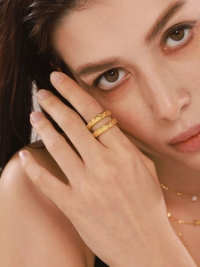 Close-up of gold plated ring with lava texture and layered star pearl necklace